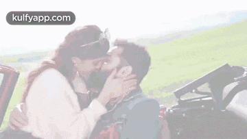 a man and a woman are kissing in the back of a car .