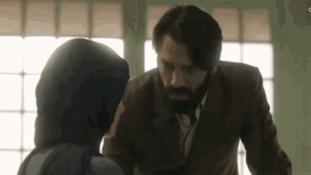 a man in a suit and tie is talking to a woman in a head scarf