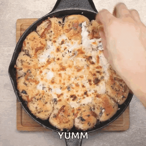 a person is dipping a piece of bread into a skillet with the word yumm written on it
