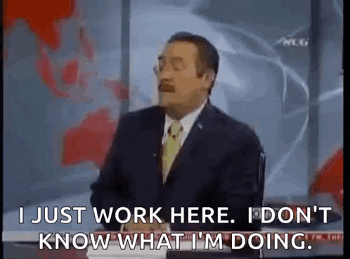 a man in a suit and tie is sitting at a desk and talking on a television .