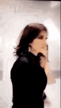 a woman in a black dress is standing in front of a mirror .