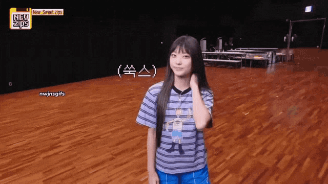a girl in a striped shirt is standing on a wooden floor in front of a sign that says new sweet 2021