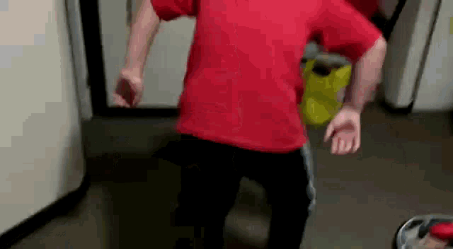 a man in a red shirt is dancing in a room .