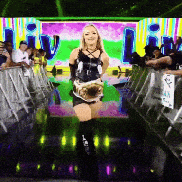 a woman in a black dress is holding a wrestling championship