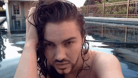 a man with long hair and a beard looks at the camera