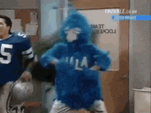 a man in a blue jersey with the number 5 on it is standing next to a man in a blue costume .