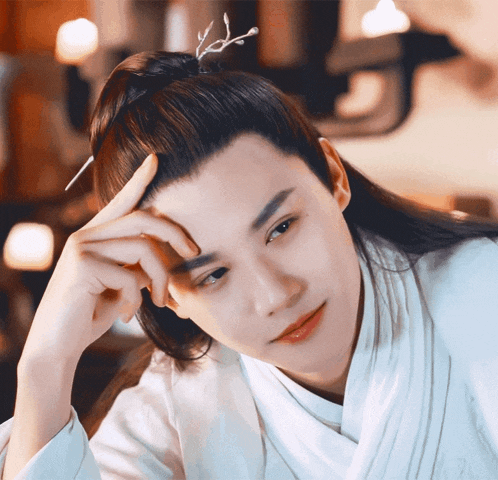a man with long hair and a ponytail has his hand on his head