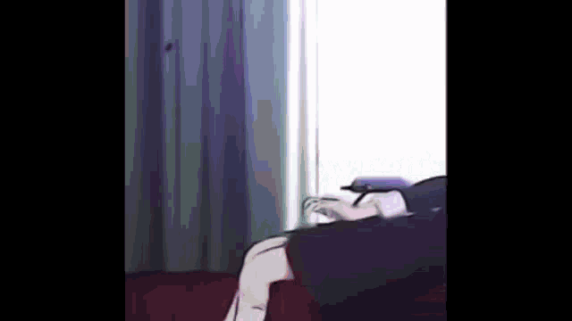 a woman is sitting on a couch in front of a window with her legs crossed .