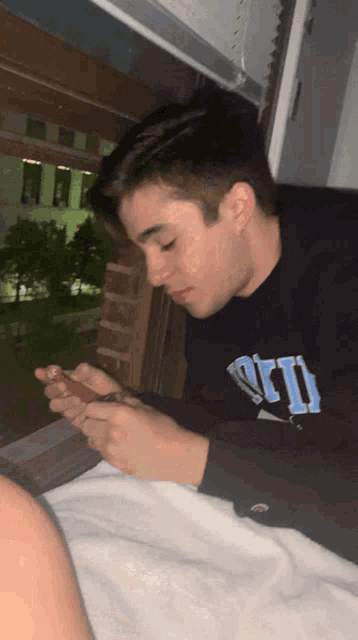 a young man wearing a black shirt that says ari is looking at his phone