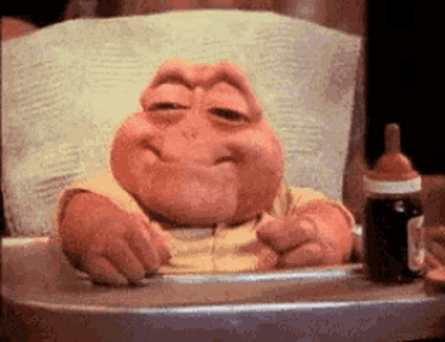 a cartoon baby is sitting in a high chair next to a bottle of medicine .