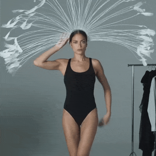 a woman in a black bodysuit is wearing a white headpiece