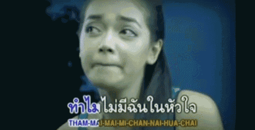 a woman is making a funny face in front of a sign that says tham-mi-mai-chan-nai-hua-chai