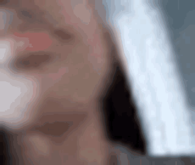 a blurry picture of a woman 's face with a white shirt on .