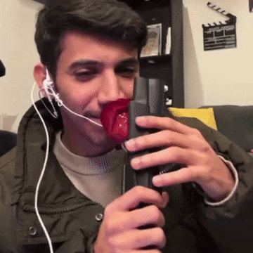 a man wearing ear buds is holding a microphone with a red rose in his mouth