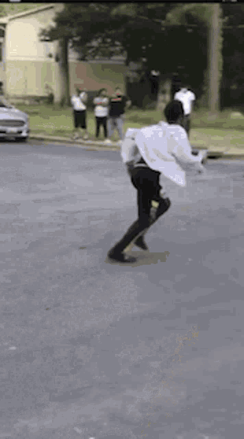 a man in a white shirt and black pants is walking down a street .