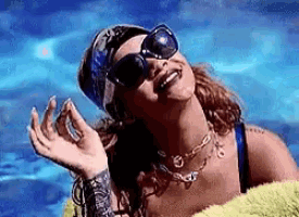 a woman wearing sunglasses and a bandana is laying in a swimming pool .