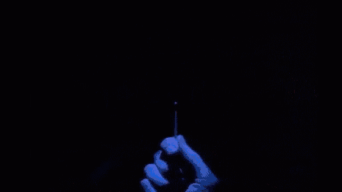 a person is holding a lighter in front of a sign that says `` are you afraid of the dark '' .
