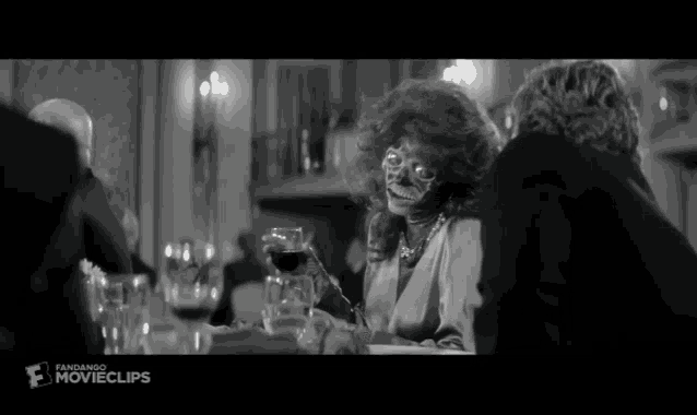 a woman with a skeleton face sits at a table with other people