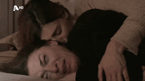 two women laying on a bed with a hd logo on the bottom