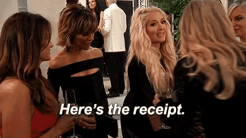 a group of women are standing next to each other holding wine glasses and talking .