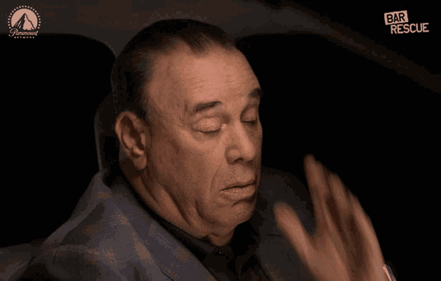 a man in a suit is sitting in the back seat of a car with a paramount network logo in the background