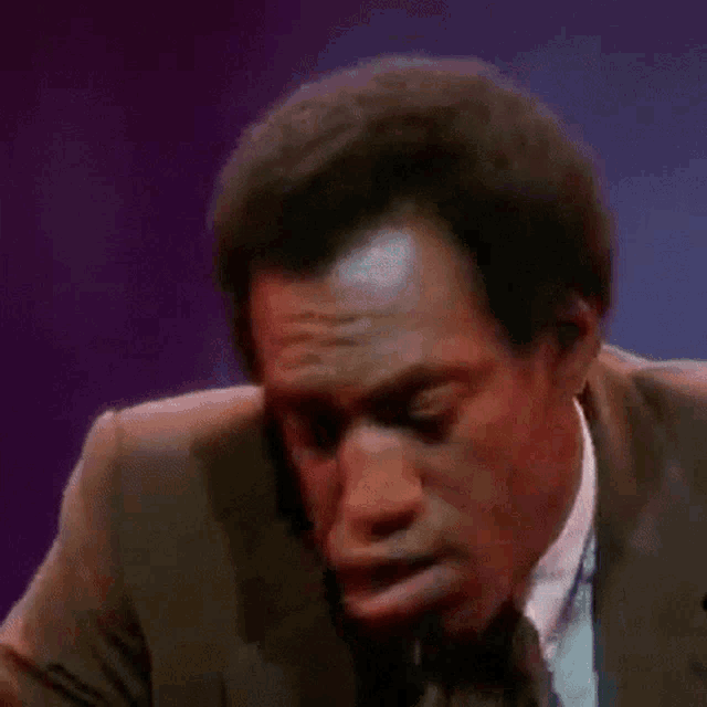 a man in a suit and tie is holding a microphone in his mouth .