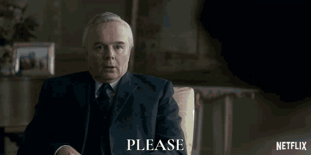 a man in a suit and tie is sitting in a chair with a netflix logo behind him