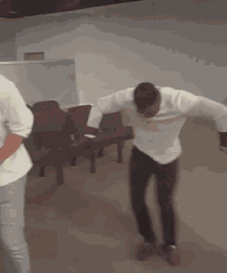 a man is dancing in a room with chairs .
