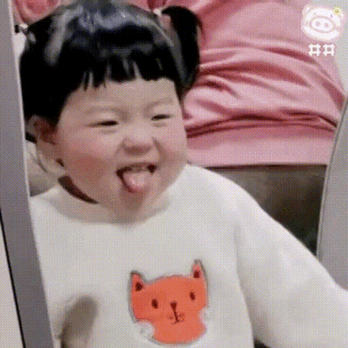 a little girl is sticking out her tongue while wearing a fox sweater .
