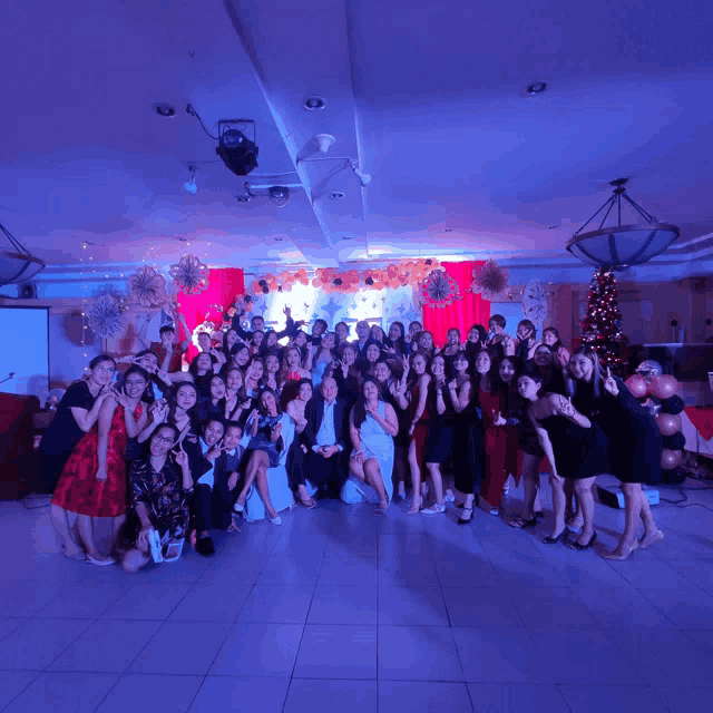 a group of people are posing for a picture in a room with a christmas tree in the background