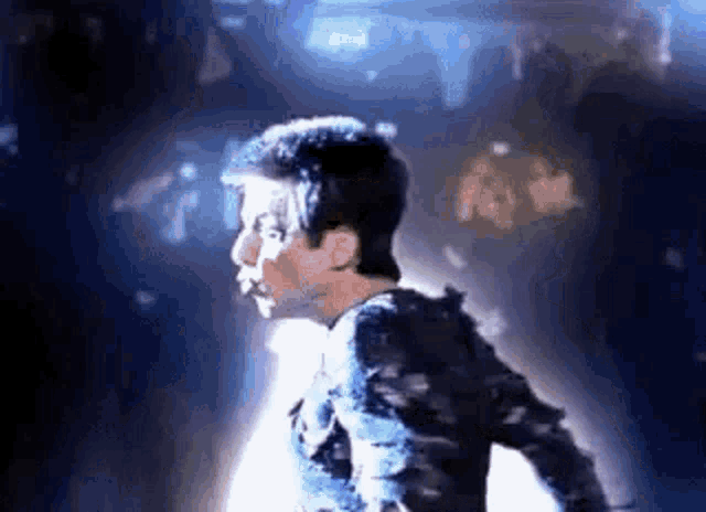 a man in a black shirt is dancing in a dark room in front of a crowd .