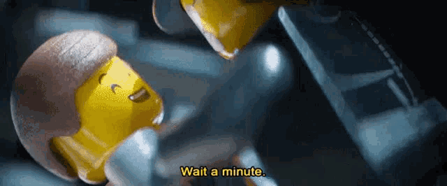 a close up of a lego figure with the words `` wait a minute '' on it .