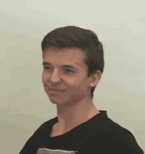 a young man wearing a black shirt is smiling and looking at the camera