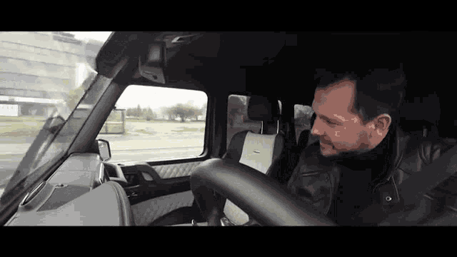 a man is sitting in the driver 's seat of a black car
