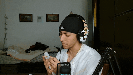 a man wearing headphones and a hat with the letter d on it looks at his phone