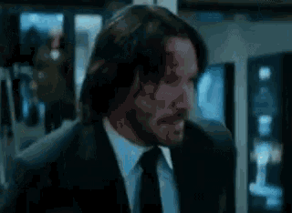 a man in a suit and tie is standing in a dark room .