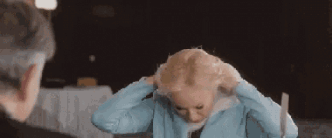 a woman in a blue jacket is holding a piece of paper in her hair .