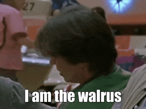 a man in a green shirt says i am the walrus in a bowling alley