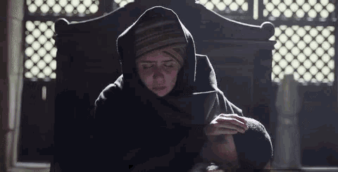 a woman in a hooded jacket is sitting in a chair with her eyes closed .