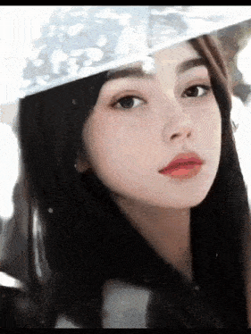 a close up of a young woman wearing a hat and looking at the camera .