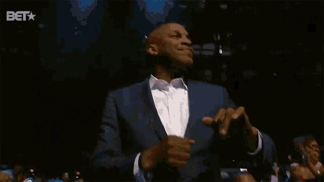 a man in a blue suit is dancing in front of a bet sign