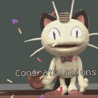 a stuffed cat is standing in front of a chalkboard with the words congratulations on it