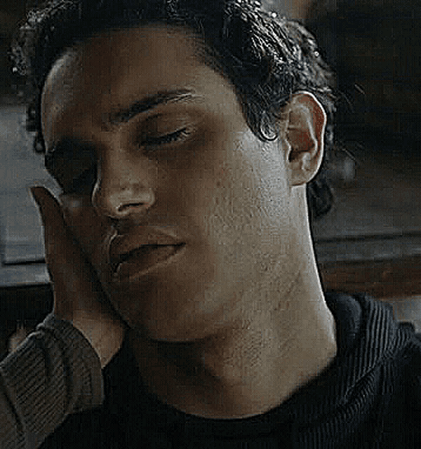 a close up of a man 's face with his eyes closed and his hand on his forehead .
