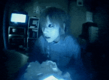 a person in a dark room with a tv in the background