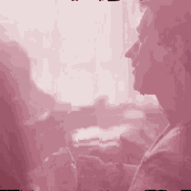 a man is sitting in front of a window in a pink room