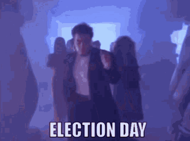 a man in a suit is dancing in a dark room and the words election day are visible