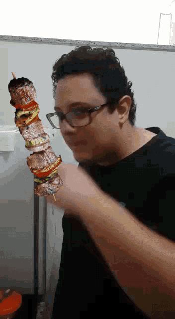 a man with glasses is holding a skewer of food