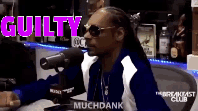 snoop dogg is talking into a microphone while wearing sunglasses and a blue and white jacket .