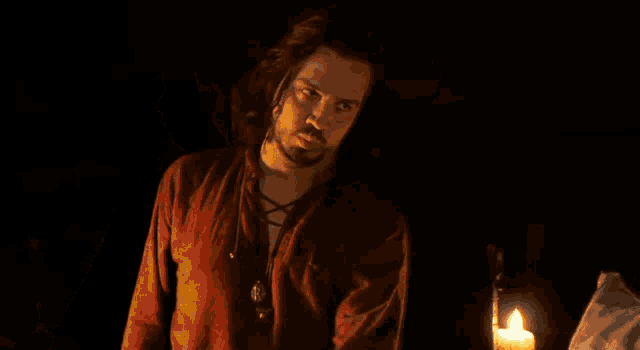 a man in a red shirt stands in the dark with his eyes closed