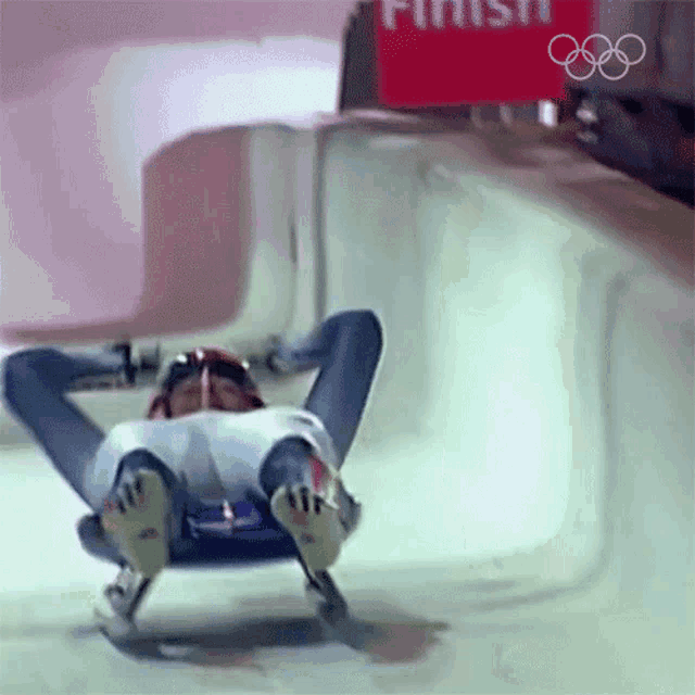 a person is sledding down a snowy track with a finish sign in the background